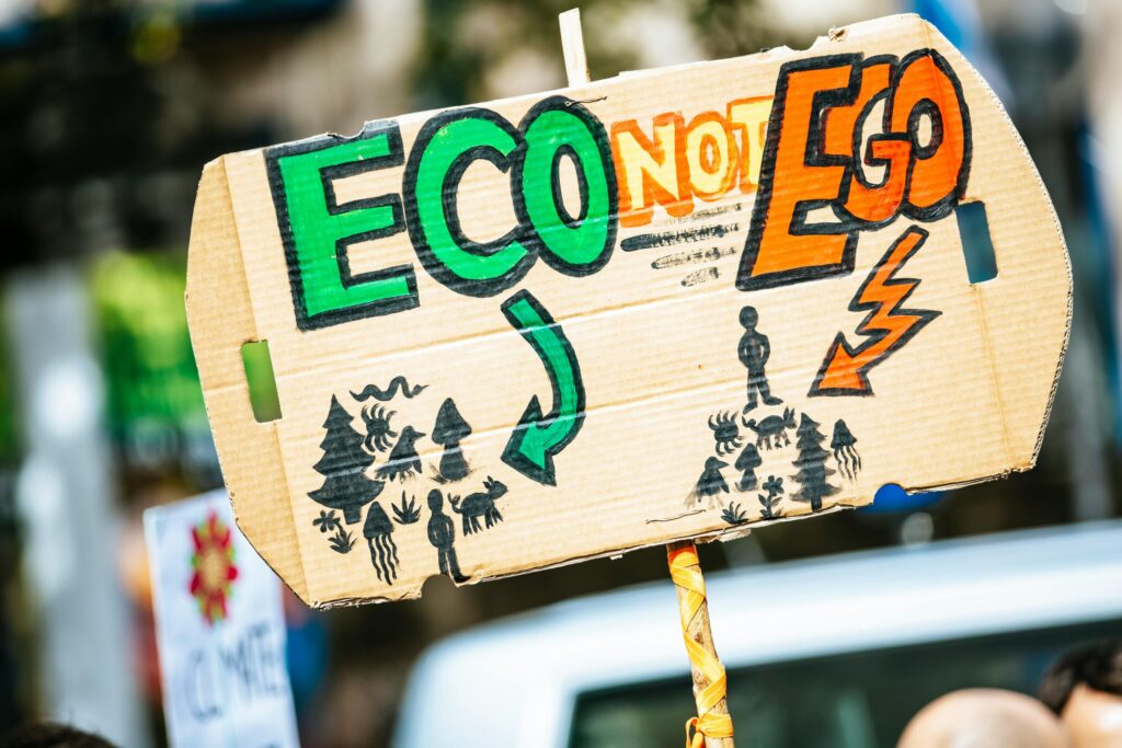 pexels-photo-2990612-2990612 Close-up of a cardboard protest sign with 'Eco Not Ego' message at a climate rally.